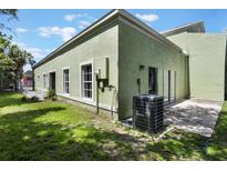 An exterior view of a green home featuring a green backyard and patio area with white trim at 1065 Universal Rest Pl, Kissimmee, FL 34744
