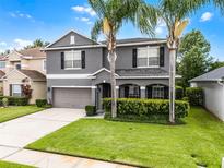 Charming gray two-story home featuring manicured lawn, palm trees, and a two-car garage at 13431 Early Frost Cir, Orlando, FL 32828