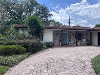 Charming brick home featuring a brick driveway, manicured landscaping, and a welcoming front porch with seating at 1420 Knollwood St, Orlando, FL 32804