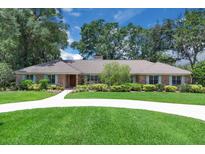 Beautiful single-story brick home featuring a long driveway, lush landscaping, and mature trees at 202 Riverview Dr, Longwood, FL 32779