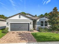 Beautiful one-story home featuring a brick driveway, gray paint, and stone veneer accents at 2247 Marsh Sedge Ln, Winter Park, FL 32792
