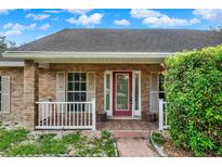 Charming brick home featuring a red front door with decorative glass and white shutters, enhancing its curb appeal at 295 Maguire St, Deltona, FL 32725