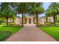 Elegant home featuring a brick driveway, manicured lawn, and tropical landscaping at 3426 Cocard Ct, Windermere, FL 34786