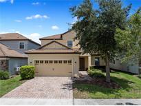 Charming two-story home featuring a tile roof, brick driveway, and well-maintained landscaping at 9023 Shadow Mountain St, Davenport, FL 33896