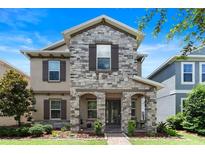 Charming two-story home featuring stone accents, a covered porch, and manicured landscaping at 15448 Murcott Blossom Blvd, Winter Garden, FL 34787