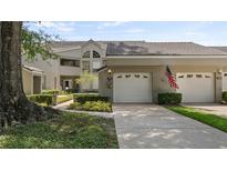 A well-maintained exterior view of a condo with a one-car garage and an American flag at 165 Durham Pl # 165, Longwood, FL 32779