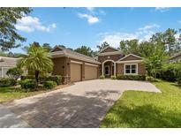Charming home featuring stone accents, lush landscaping, brick driveway, and a welcoming facade at 207 Spalding Way, Deland, FL 32724