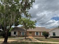 Charming single-story brick home featuring a well-maintained lawn, mature trees and inviting facade at 3917 Lake Mira Dr, Orlando, FL 32817