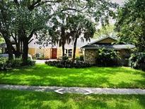 Charming single-story home featuring a red door and beautifully landscaped front yard with lush green grass at 4140 Winderlakes Dr, Orlando, FL 32835