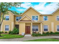 Charming two-story townhome with yellow siding, a well-manicured lawn, and a welcoming front porch area at 835 Grand Regency Pt # 104, Altamonte Springs, FL 32714