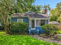 Charming single-story home features a brick chimney, blue siding, and a cozy front porch, surrounded by lush landscaping at 1642 Mount Vernon St, Orlando, FL 32803