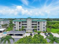 Multi-story condo building with parking, green roof and landscaping against a sunny sky at 426 Bouchelle Dr # 202, New Smyrna Beach, FL 32169