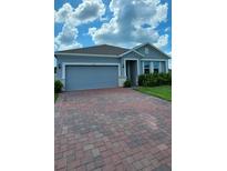Charming single-story home featuring a paved driveway and attached two-car garage at 483 Shadow Gorge Way, Eustis, FL 32736