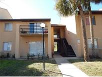 Two-story condo building featuring a balcony and staircase, surrounded by palm trees at 5220 Via Hacienda # 212, Orlando, FL 32839