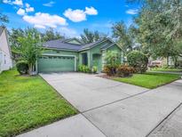 Charming green home featuring a lush landscaped yard, large driveway, and a well-manicured lawn at 5263 Beach River Road, Windermere, FL 34786