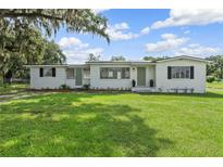 Charming single-story home featuring a freshly painted exterior, lush green lawn, and beautiful mature trees at 5521 Makoma Dr, Orlando, FL 32839