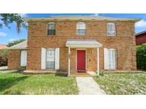 Charming brick two-story home featuring a bright red front door and white window shutters at 5891 Sir Henry Rd, Orlando, FL 32808