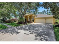 Inviting yellow home featuring a three-car garage, manicured lawn, mature trees, and a covered front entry at 6092 Sabal Hammock Cir, Port Orange, FL 32128