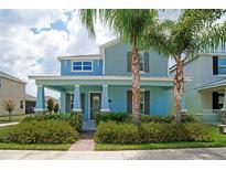 Charming two-story home with a welcoming front porch, lush landscaping, and beautiful palm trees at 7530 Summerlake Groves St, Winter Garden, FL 34787