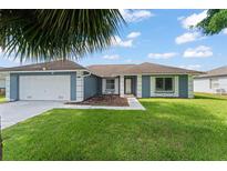 Charming single-story home featuring a well-maintained lawn, two car garage, and inviting front entrance at 7764 Indian Ridge N Trl, Kissimmee, FL 34747