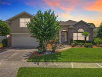 Charming two-story home with brick accents, landscaped yard and flowering tree at 106 Winghurst Blvd, Orlando, FL 32828