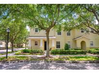 Charming yellow two-story townhome featuring lush landscaping and a welcoming front entrance at 13028 Auburn Cove Ln, Orlando, FL 32828