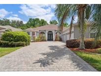 Charming home featuring a lovely paved driveway, lush landscaping, and a welcoming blue front door at 1542 Wescott Loop, Winter Springs, FL 32708