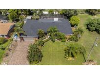 An aerial view of a one-story house with a brick driveway, a screened-in pool, and a lush green lawn at 209 7Th S St, Haines City, FL 33844