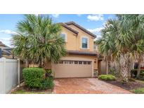 Stunning two-story home featuring a brick driveway, two-car garage, and beautiful palm trees at 2121 Morocco Way, Kissimmee, FL 34747