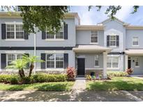 Charming townhome featuring a well-manicured front yard with lush landscaping and stone accents at 2211 J Lawson Blvd, Orlando, FL 32824