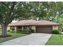 Charming brick home with a well-manicured lawn, mature trees, and a two-car garage at 26 Canter Club Ct, Debary, FL 32713
