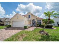 Charming single-story home featuring a manicured lawn, mature palm tree, and brick-paved walkway leading to the entryway at 3585 Ventura Club Cir, Orlando, FL 32822