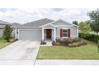 Charming single-story home with well-manicured lawn, gray siding, and a pop of color from the red front door and shutter at 561 Andrea S Cir, Haines City, FL 33844