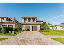 Two-story home featuring a tile roof, two-car garage, and a paver driveway at 15942 Vetta Dr, Bella Collina, FL 34756