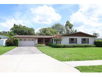 Charming single-story home with a manicured lawn, mature trees, and a driveway leading to an attached garage at 2417 Bayfront Pkwy, Orlando, FL 32806
