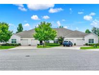 Well-manicured front exterior of neutral colored home with three garage doors, green trees and lawn and blue sky at 3210 Sonesta Ct # B, Clermont, FL 34711