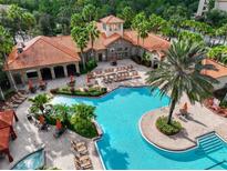 An aerial view of community pool with lounge chairs and umbrellas surrounded by tropical landscaping and clubhouse at 8020 Tuscany Way # 6301, Davenport, FL 33896