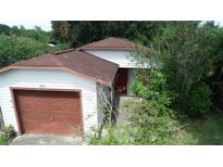 Quaint one-story home with a brown roof, attached garage and mature trees at 1612 Eastern Ave, St Cloud, FL 34771