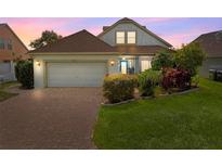 Charming single-Gathering home with a brick driveway and well-maintained landscaping at dusk at 2076 Shannon Lakes Blvd, Kissimmee, FL 34743