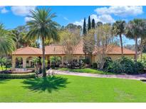 Stunning single-story home featuring a terracotta roof, lush landscaping, and a circular driveway at 3130 Butler Bay N Dr, Windermere, FL 34786