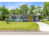 Charming single-story home with a well-manicured lawn, covered parking and a bright yellow front door at 3515 Leslie Dr, Orlando, FL 32806