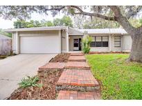 Charming single-story home with brick pathway and a well-manicured lawn under a mature tree at 452 Sundown Trl, Casselberry, FL 32707