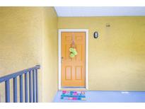 Welcoming yellow door adorned with a wreath and a cheerful doormat, inviting you to come inside at 5259 Images Cir # 301, Kissimmee, FL 34746
