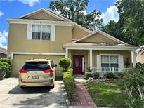 Charming two-story home with a red front door, attached garage, and manicured landscaping at 7939 Riffle Ln, Orlando, FL 32818