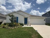 Charming single-story home with a well-manicured lawn, blue door, and two car garage at 873 Daring Dr, Davenport, FL 33837