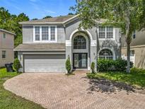Stunning two-story home featuring a brick driveway, two-car garage, and beautifully landscaped front yard at 9454 Candice Ct, Orlando, FL 32832