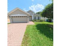 Charming single-story home featuring a manicured lawn, brick paved drive, and a two-car garage at 9982 Shadow Creek Dr, Orlando, FL 32832