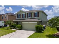Charming two-story home featuring lush landscaping, an attached two car garage, and an inviting facade at 1951 Betsy Ross Ln, St Cloud, FL 34769