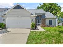 Charming single-story home with a two-car garage, lush green lawn, and beautiful landscaping at 10473 Glassborough Dr, Orlando, FL 32825
