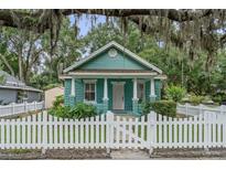 Charming blue cottage-style home with a white picket fence and mature landscaping at 121 W Oakland Ave, Oakland, FL 34760